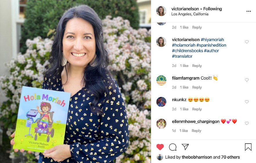 Inés holding Hola Moriah children's book by Victoria Nelson